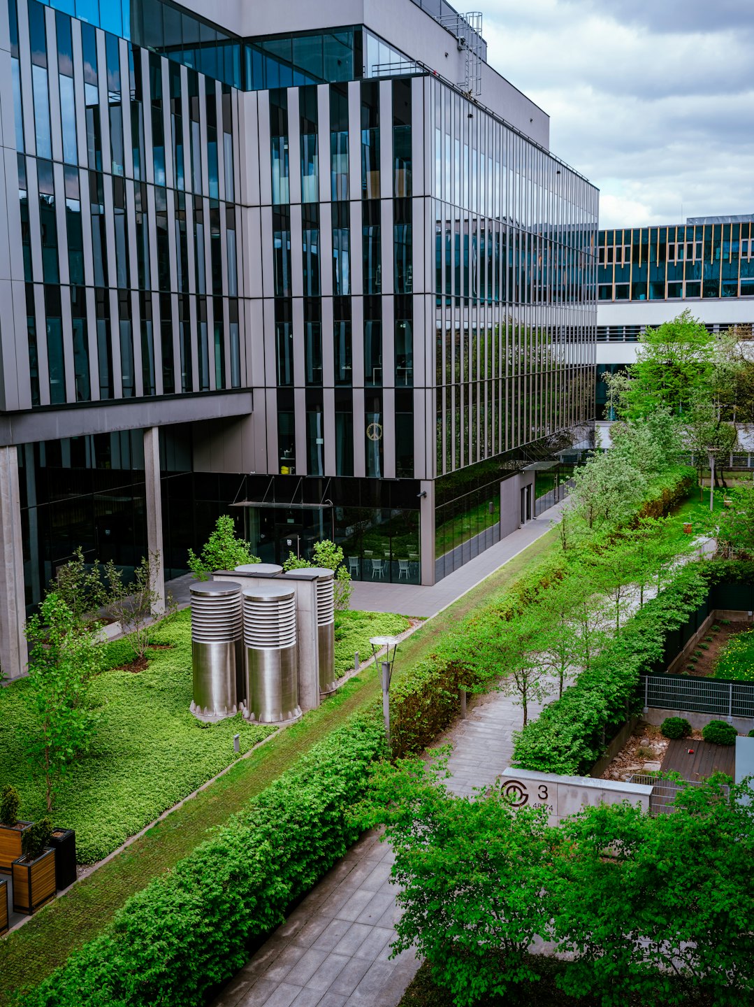 Modern glass office building surrounded by lush green landscaping.